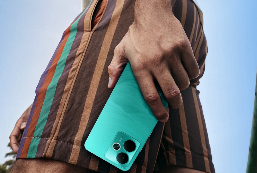 Muž drží zelený Realme 14T 5G na pláži, zdůrazňující jeho odolnost.