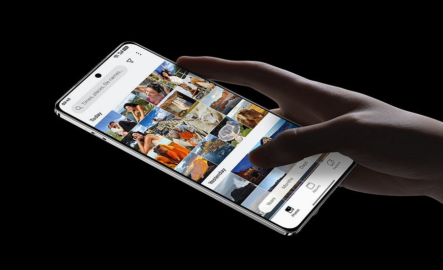 Ruka drží telefon OnePlus 13 5G s rozsvíceným displejem zobrazujícím galerii fotografií a uživatelské rozhraní OxygenOS 15.
