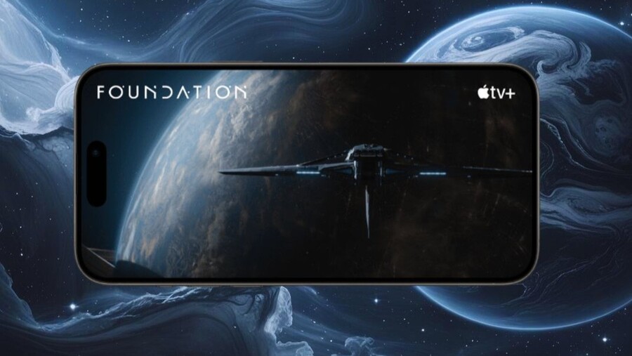 iPhone 15 Pro Max zobrazuje scénu z filmu Foundation z aplikace Apple TV+ na svém displeji. Telefon symbolizuje celodenní výdrž baterie, která je dostatečně velká, aby umožnila sledování filmů a další náročné aktivity.
