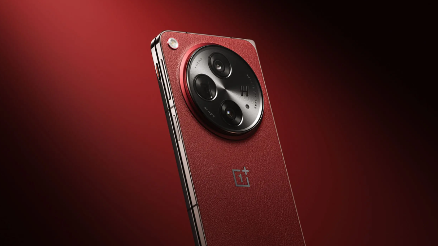 Detailní pohled na zadní stranu červeného telefonu OnePlus Open Apex Edition. Velký kruhový modul fotoaparátů je na lesklém, kovovém povrchu, obklopený texturovanou, vínově červenou zadní částí.