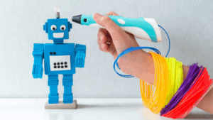 Dítě sedí u stolu a soustředěně kreslí robota pomocí 3D pera.