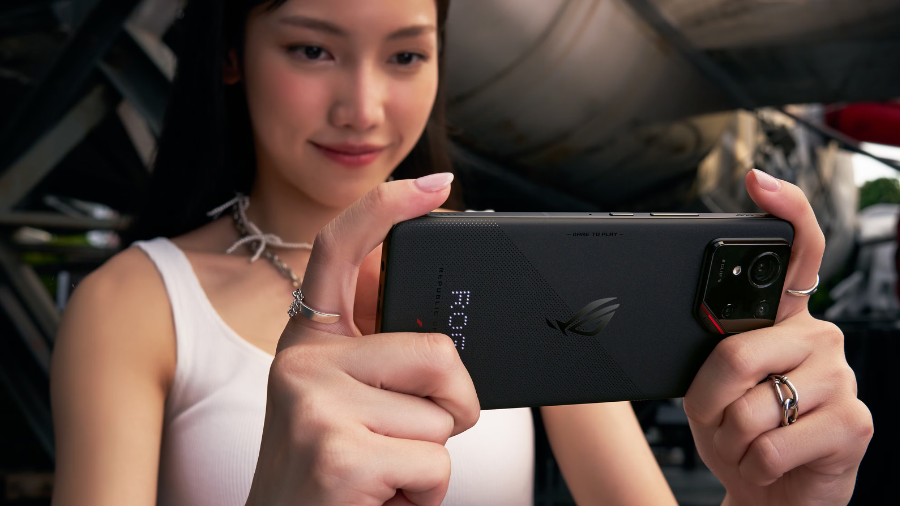 Mladá žena drží černý ASUS ROG Phone 9 na šířku a hraje hru, viditelné jsou ramenní plošky AirTrigger.