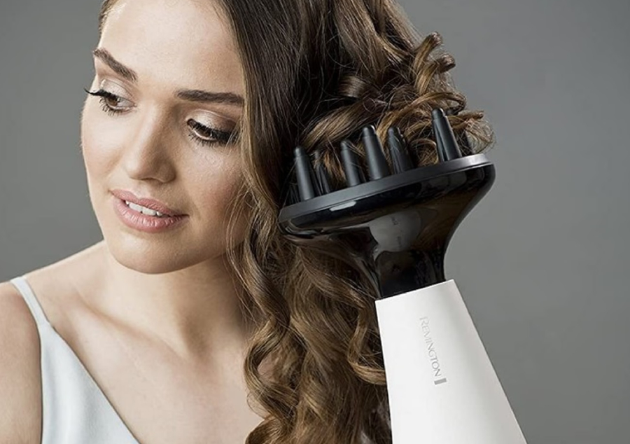 Žena s hnědými vlasy fénující si vlasy fénem Remington Proluxe AC9140, na kterém je nasazený difuzér pro vytvoření vln.