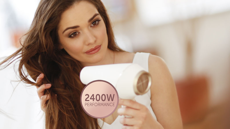 Žena s dlouhými hustými hnědými vlasy si fénuje vlasy fénem Remington Proluxe AC9140, na fotografii je ikonka s hodnotou příkonu 2 400 W. 