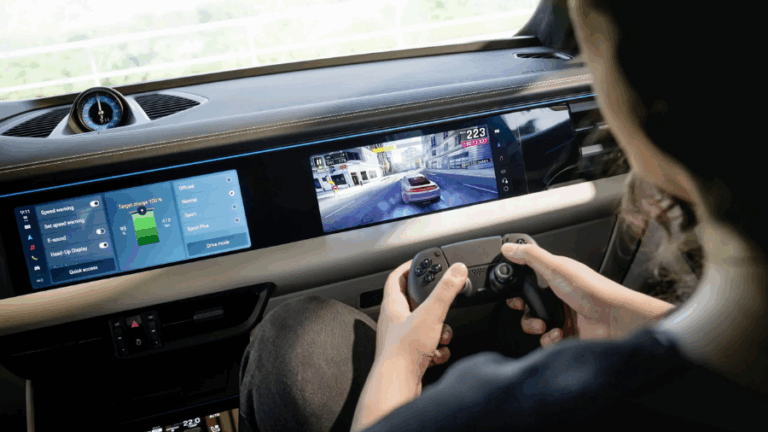 Člověk sedí v Porsche Macan a hraje závodní hru pomocí ovladače, uvnitř vozu je vidět centrální displej a interiér.