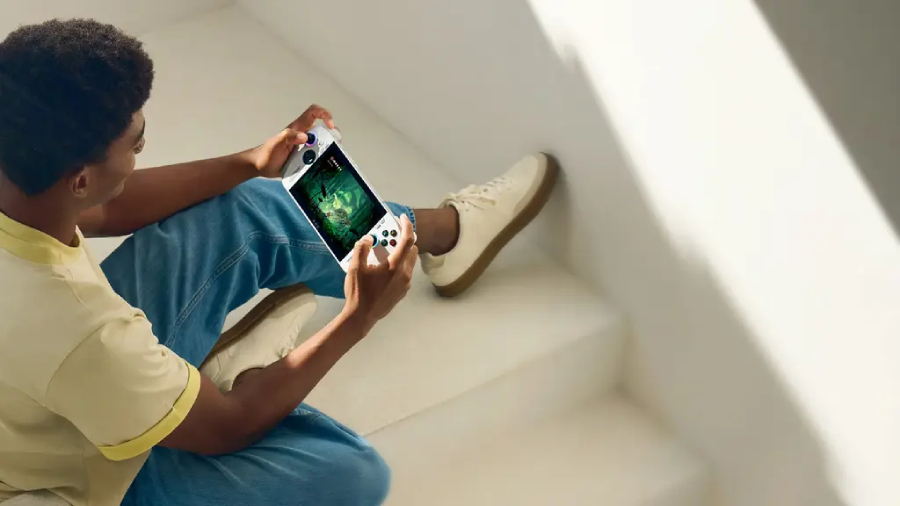 Teenager sedí na schodech, drží v ruce kapesní Xbox a hraje hru.