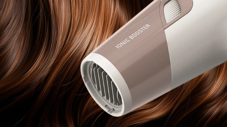 Rowenta Studio Dry Glow CV5831F0 v bílém provedení, detailní pohled na přední mřížku fénu, na pozadí s leklými hnědými vlasy.