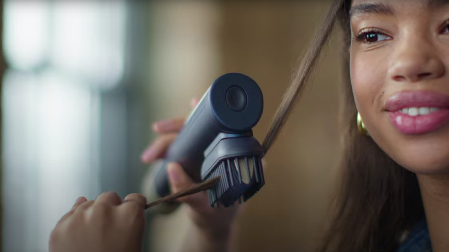 Žena, která si rovná pramen vlasů fénem BaByliss Air Wand 3v1.