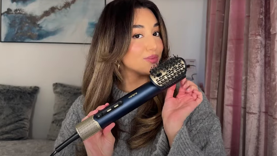 Žena s dlouhými vyfoukanými vlasy držící fén BaByliss Air Wand 3v1.