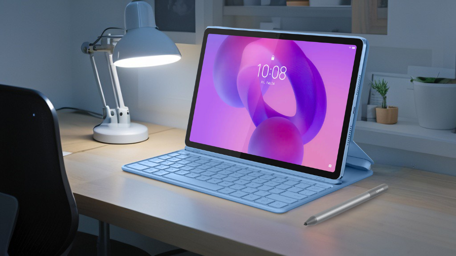 Světle modrý tablet Lenovo Idea Tab 11" s připojenou klávesnicí a stylusem na dřevěném stole pod stolní lampou.