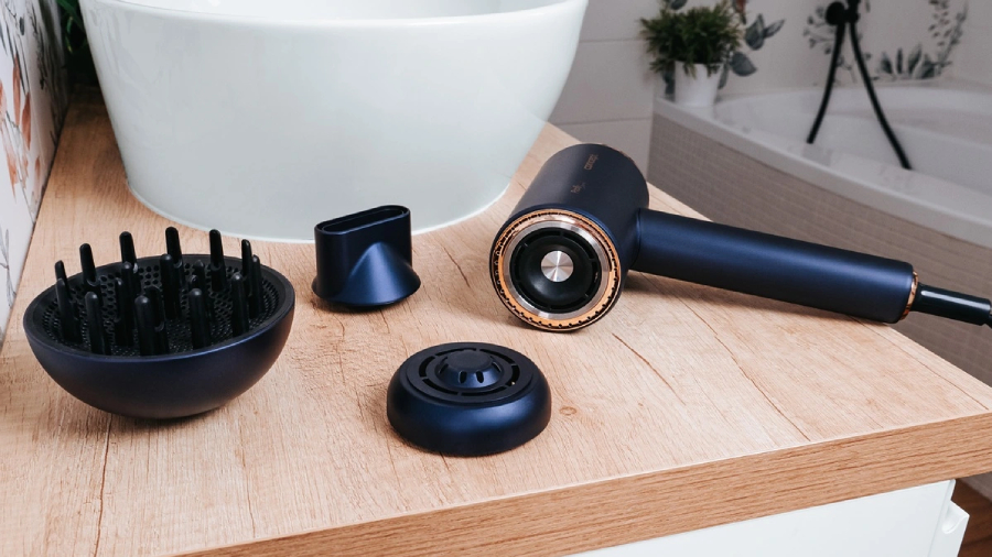 Fén Concept BLDC VV8100 ležící v koupelně vedle umyvadla i se všemi jeho nástavci.