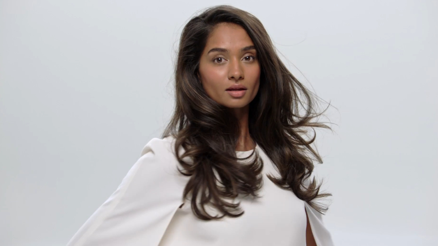 Žena s dlouhými hnědými a  upravenými vlasy fénem Dyson Supersonic r HD18.