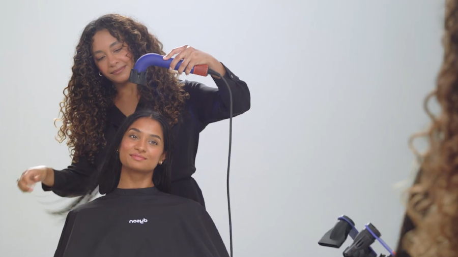 Stylistka fénující vlasy ženě fénem Dyson Supersonic r HD18.