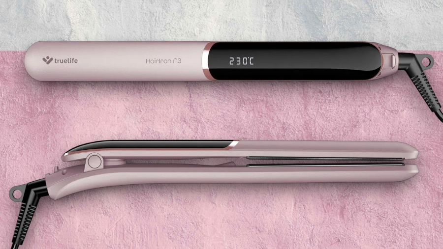 Žehlička na vlasy TrueLife HairIron N3 z pohledu shora a z boku při zamčených destičkách ležící na bílo-růžovém podkladu.