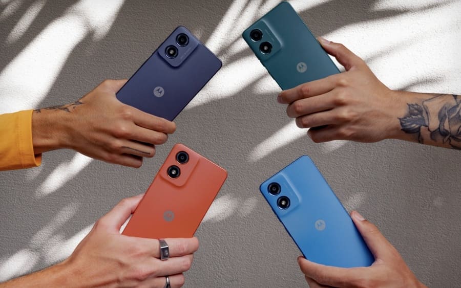 Zadní strana s fotoaparátem a logem telefonu Motorola Moto G06 Power v rukou čtyř lidí.