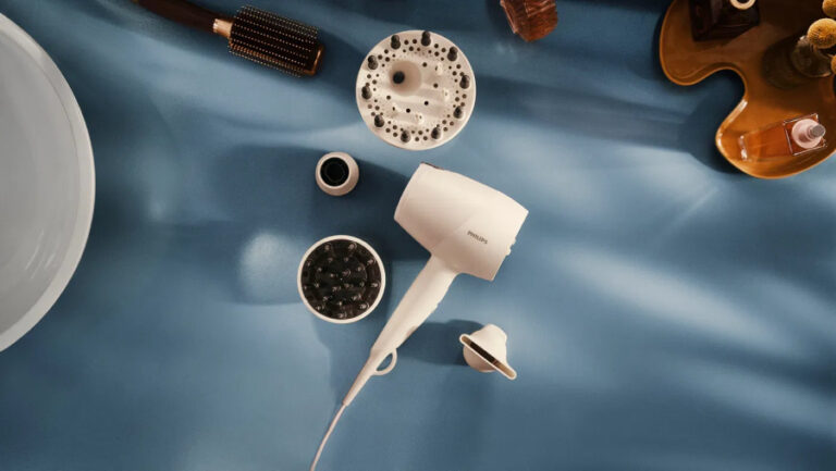 Fén Philips Series 9000 SenseIQ ležící na modrém stole i s jeho příslušenstvím.