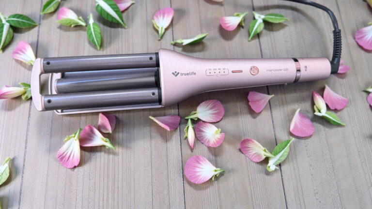 Trojkulma na vlasy TrueLife HairWaver W6 v růžovém provedení položená na dřevěné ploše na které jsou poházené růžové okvětní lístky.