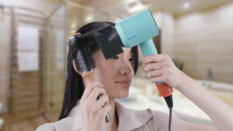 Asijská žena fénující si vlasy fénem Dyson Supersonic Nural a tvaruje si pramen vlasů pomocí kulatého kartáče.
