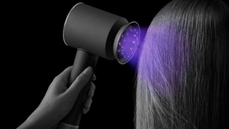 Černobílý obrázek fénu Dyson Supersonic Nural, který drží žena v ruce a fénuje si vlasy. Na černobílém obrázku je vizuálně fialově vyznačený proud vzduchu, tak aby vynikl.