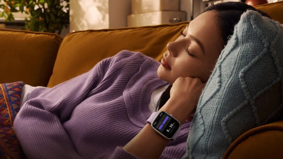 Tipy na vánoční dárky pro ženy: Žena odpočívá na gauči a má na ruce chytré hodinky Xiaomi Redmi Watch 5 s fialovým řemínkem, na jejichž displeji je vidět monitorování spánku.