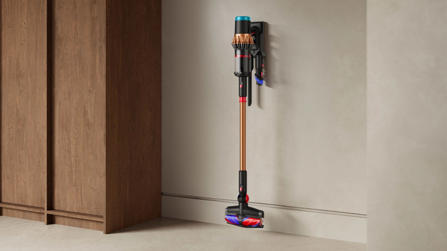 Akumulátorový vysavač Dyson V16 Piston Animal v měděno-černém provedení elegantně uložený v nástěnném držáku, který slouží k jeho nabíjení a přehlednému uložení příslušenství v moderním interiéru.