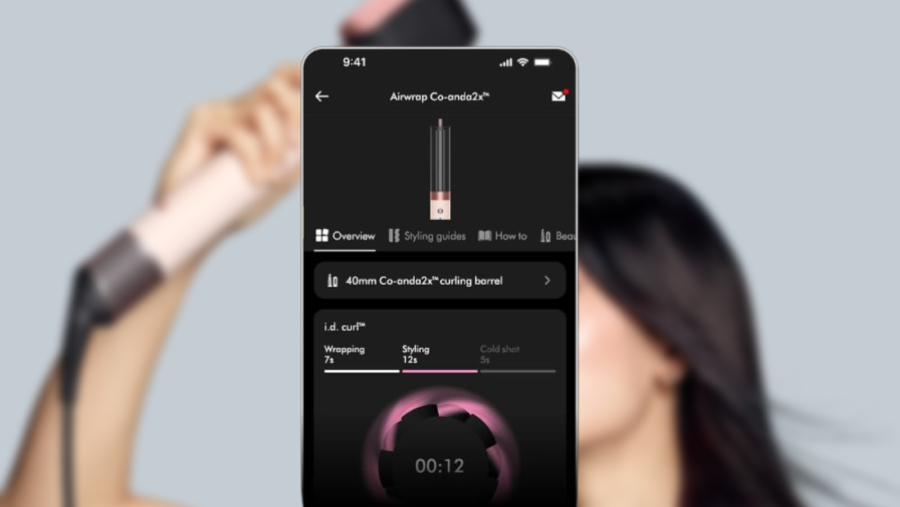 Detail aplikace MyDyson™ s časovačem pro i.d. curl™ u kulmofénu Dyson Airwrap Co-anda 2x™ na pozadí s modelkou.