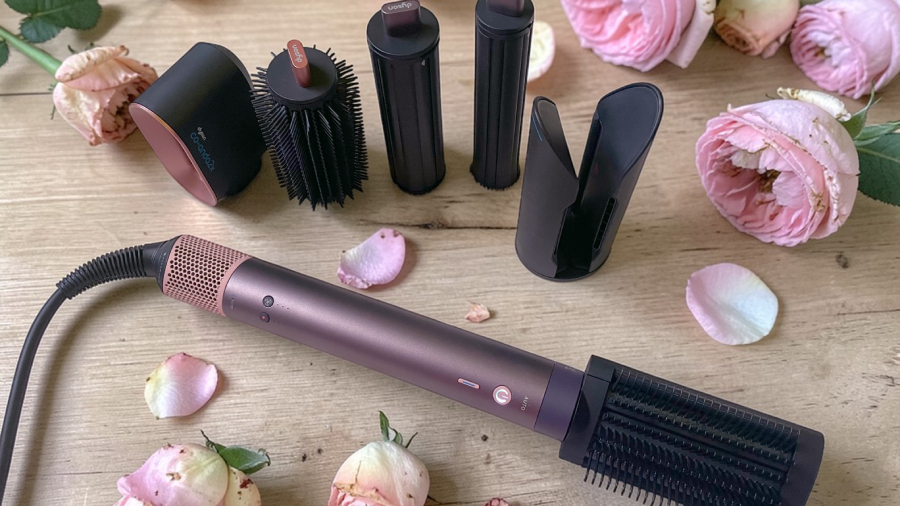 Rozložené inteligentní nástavce a tělo pro kulmofén Dyson Airwrap Co-anda 2x™ v luxusním provedení Jasper Plum na dřevěném stole s růžemi.