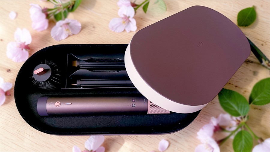 Otevřený úložný kufřík pro kulmofén Dyson Airwrap Co-anda 2x™ v barvě Jasper Plum obklopený květy třešní na světlém dřevě.