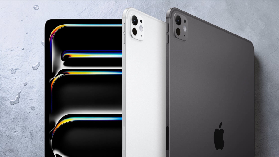 Detailní pohled na nové tablety Apple iPad Pro 13" M5 v barevných variantách Silver a Space Black. Obrázek ukazuje zářivý displej s abstraktní tapetou, tenký boční profil a zadní stranu s logem Apple na mokrém břidlicovém podkladu.