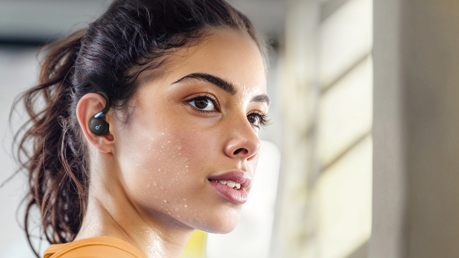 Detailní pohled na sportovkyni s nasazeným černým sluchátkem Soundcore Sport X20. Snímek zdůrazňuje odolnost proti potu a bezpečné uchycení pomocí nastavitelného háčku během intenzivního tréninku.