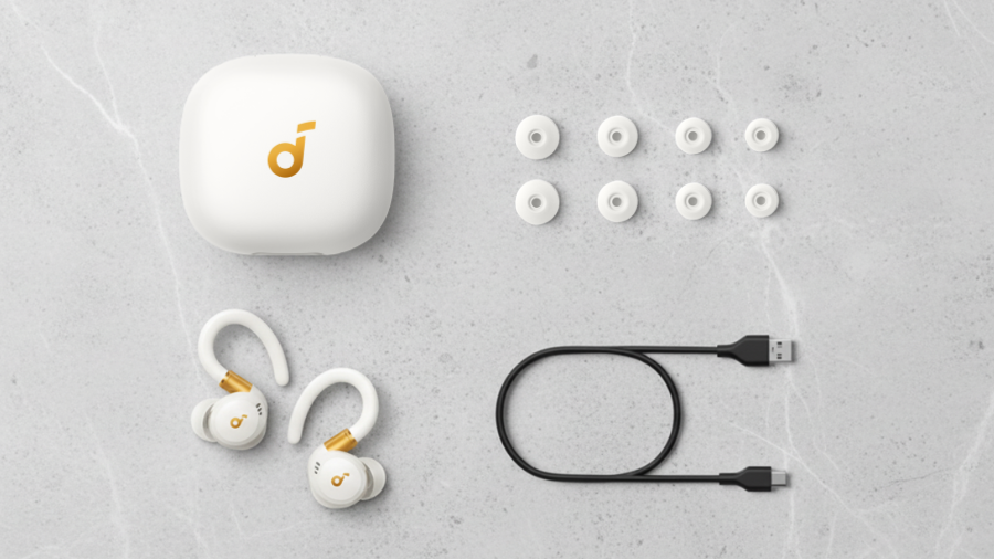 Obsah balení sluchátek Soundcore Sport X20 v bílé variantě: otevřené nabíjecí pouzdro, dvojice sluchátek s ušními háčky, USB-C nabíjecí kabel a čtyři náhradní páry silikonových špuntů různých velikostí.