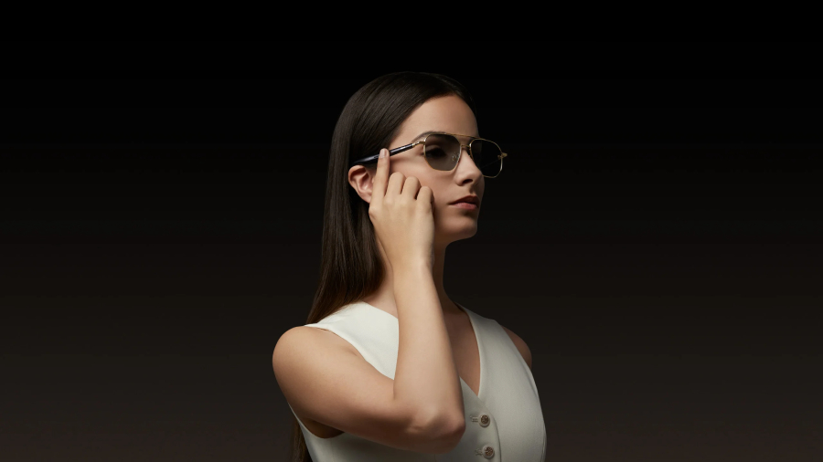 Žena v bílém oblečení používá dotykové ovládání na stranici pro audio brýle Mijia Smart Audio Glasses v elegantním provedení Pilot se zlatými obroučkami.