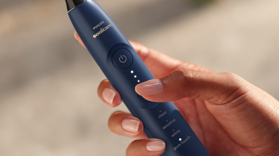 Žena nastavuje program pomocí tlačítka na zubním kartáčku Philips Sonicare 7100