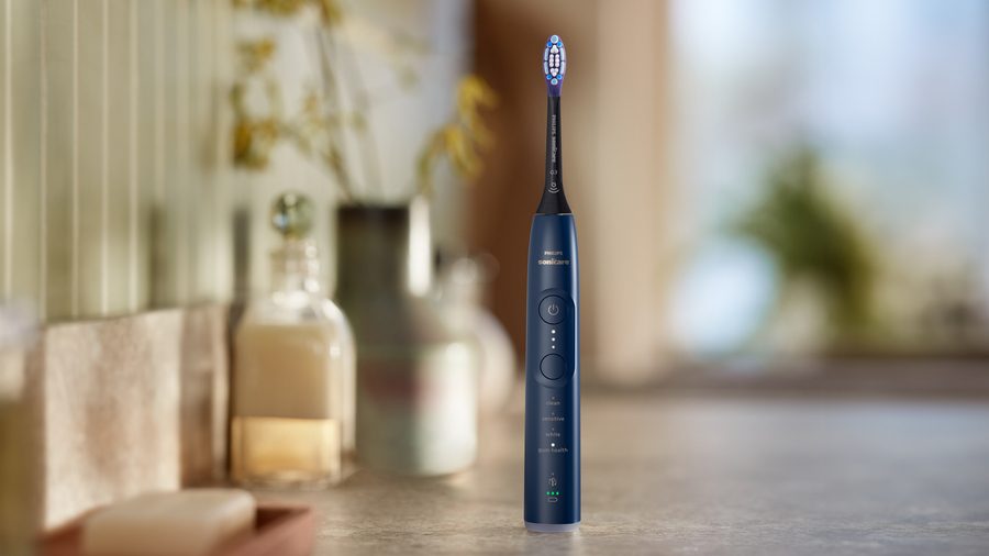 Zubní kartáček Philips Sonicare 7100 v tmavě modré barvě stojí na stole v koupelně