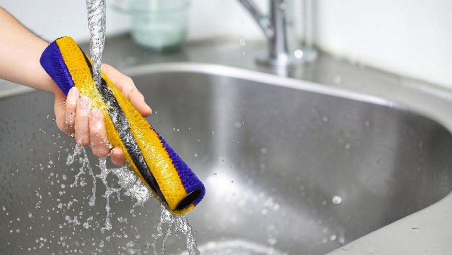 Detailní záběr na omývání fialového HEPA filtru vysavače Dyson Gen5detect Absolute pod tekoucí vodou, což zajišťuje jeho dlouhou životnost a hygienickou čistotu.