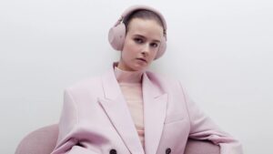 Žena v růžovém kostýmu se sluchátky Sony Noise Cancelling WH-1000XM6 v barvě Sand Pink.