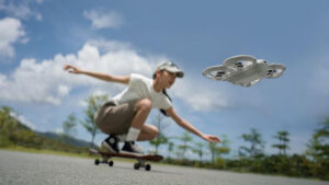 Miniaturní dron DJI Neo letí nízko nad zemí a automaticky natáčí dívku jedoucí na skateboardu za slunečného dne.