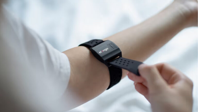 Detailní pohled na upevnění černého snímače Elonga na předloktí pro ranní měření variability srdečního tepu.
