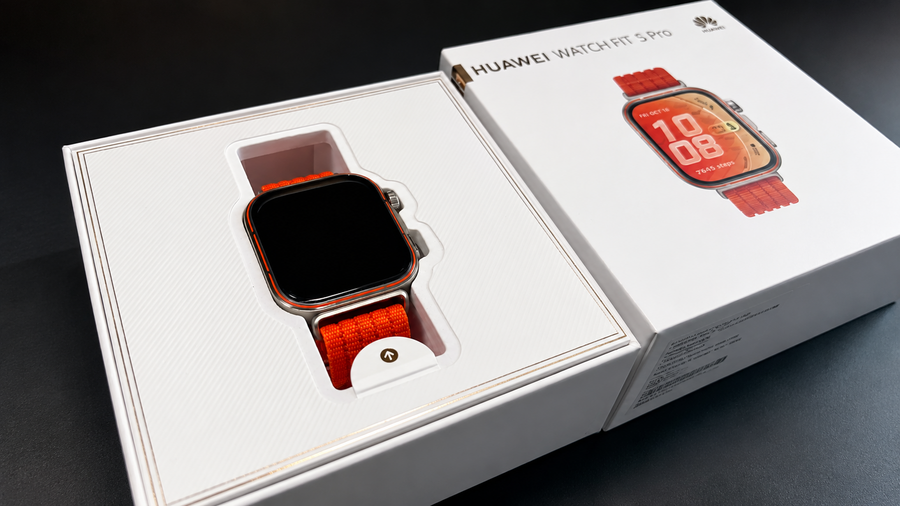 Rozbalené chytré hodinky Huawei Watch Fit 5 Pro se stříbrným tělem a výrazným oranžovým řemínkem v originální bílé krabičce.
