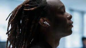 Boční profil muže s dredy, který má v uchu bezdrátové sluchátko Samsung Galaxy Buds3 Pro ve stříbrné barvě a má zavřené oči.