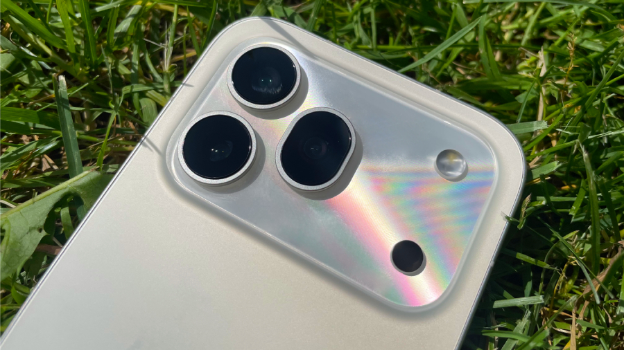 Detailní pohled na zadní fotomodul telefonu HONOR 600 Pro ukazuje perleťové odlesky lesklé části na zeleném trávníku.