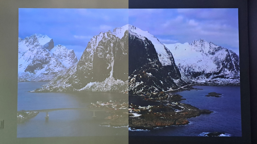 Porovnání kvality obrazu projektoru Epson EF-72 na bílé zdi. Levá polovina fotografie zachycuje promítání za denního světla s roztaženými závěsy, kdy je obraz světlejší a méně kontrastní. Pravá polovina ukazuje stejnou scénu po zatažení závěsů, kde jsou barvy výrazně sytější, černá hlubší a celkový obraz lépe čitelný.