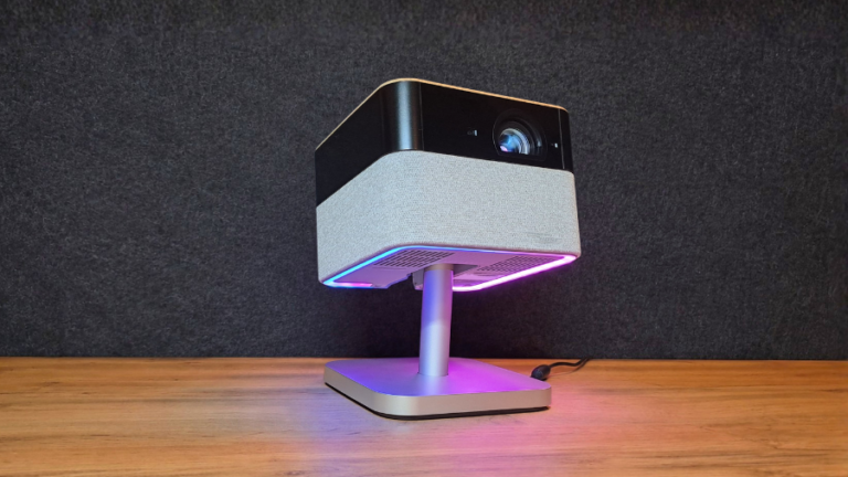 Projektor Epson EF-72 stojící na podstavci s aktivním vícebarevným RGB podsvícením základny a textilním povrchem reproduktoru.