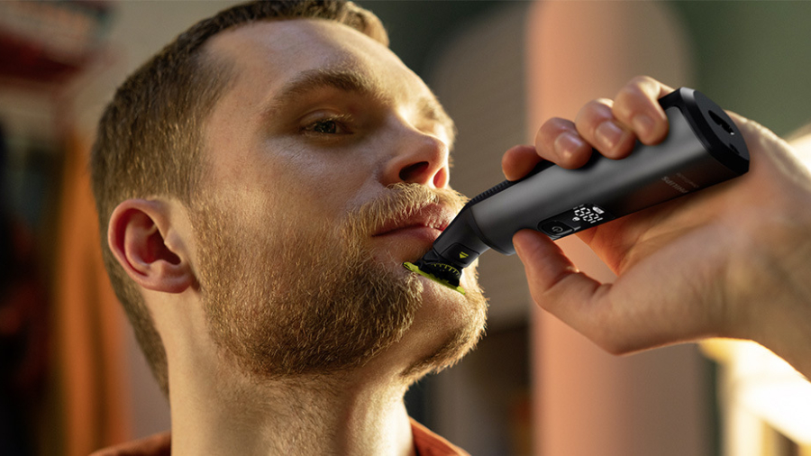 Mladý muž si precizně upravuje své vousy pomocí hybridního holicího strojku Philips OneBlade Pro 360 jako užitečný a praktický dárek pro Den otců.