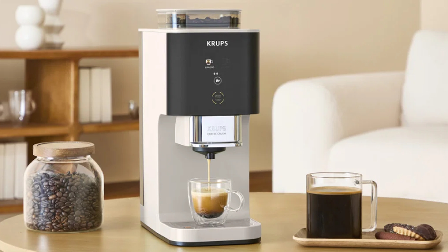 Moderní automatický kávovar KRUPS SA4001E0 Coffee Crush Ivory připravující čerstvé espresso do skleněného šálku na stole jako voňavý dárek pro Den otců.