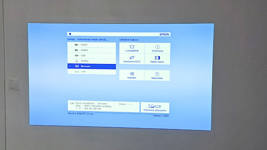 Hlavní nabídka projektoru Epson zobrazená na stěně za denního světla, s vybranou možností Miracast v seznamu zdrojů a přehledem užitečných funkcí.