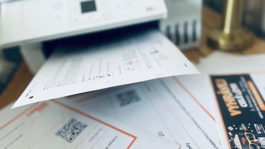 Černobílý dokument s textem a diagramem vycházející z tiskárny Epson EcoTank L3366, pod kterým leží vytištěné vstupenky s QR kódy a leták.