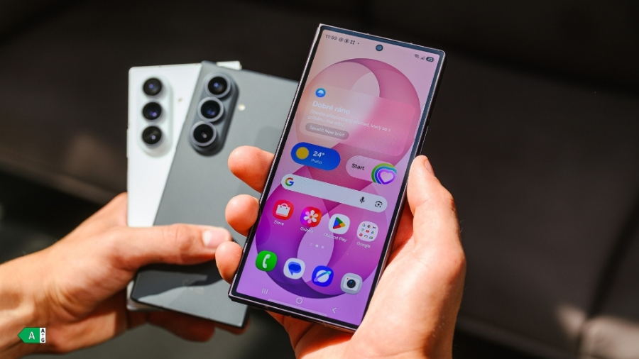 Detailní pohled na držení telefonu Samsung Galaxy Z Fold8 Ultra s rozsvíceným předním displejem a dalšími dvěma modely v pozadí.