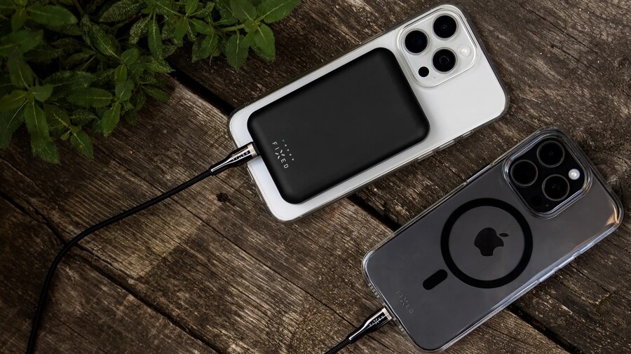 Back to school: Dva iPhony v krytech leží na dřevěném stole, přičemž k jednomu je připevněna černá powerbanka FIXED MagZen a druhý se nabíjí kabelem.