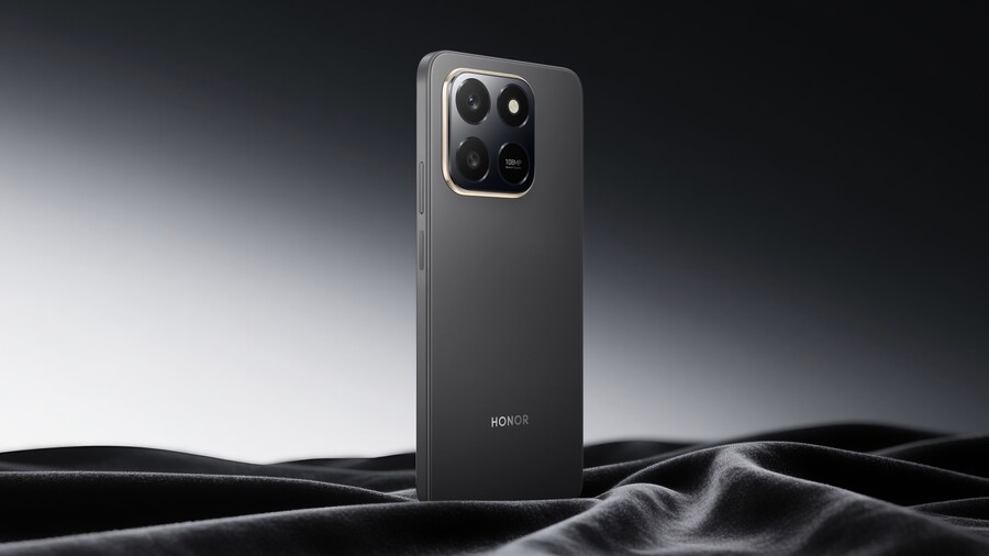Back to school: Černý chytrý telefon HONOR X7d s výrazným fotomodulem stojí na řasené černé látce na tmavém pozadí.